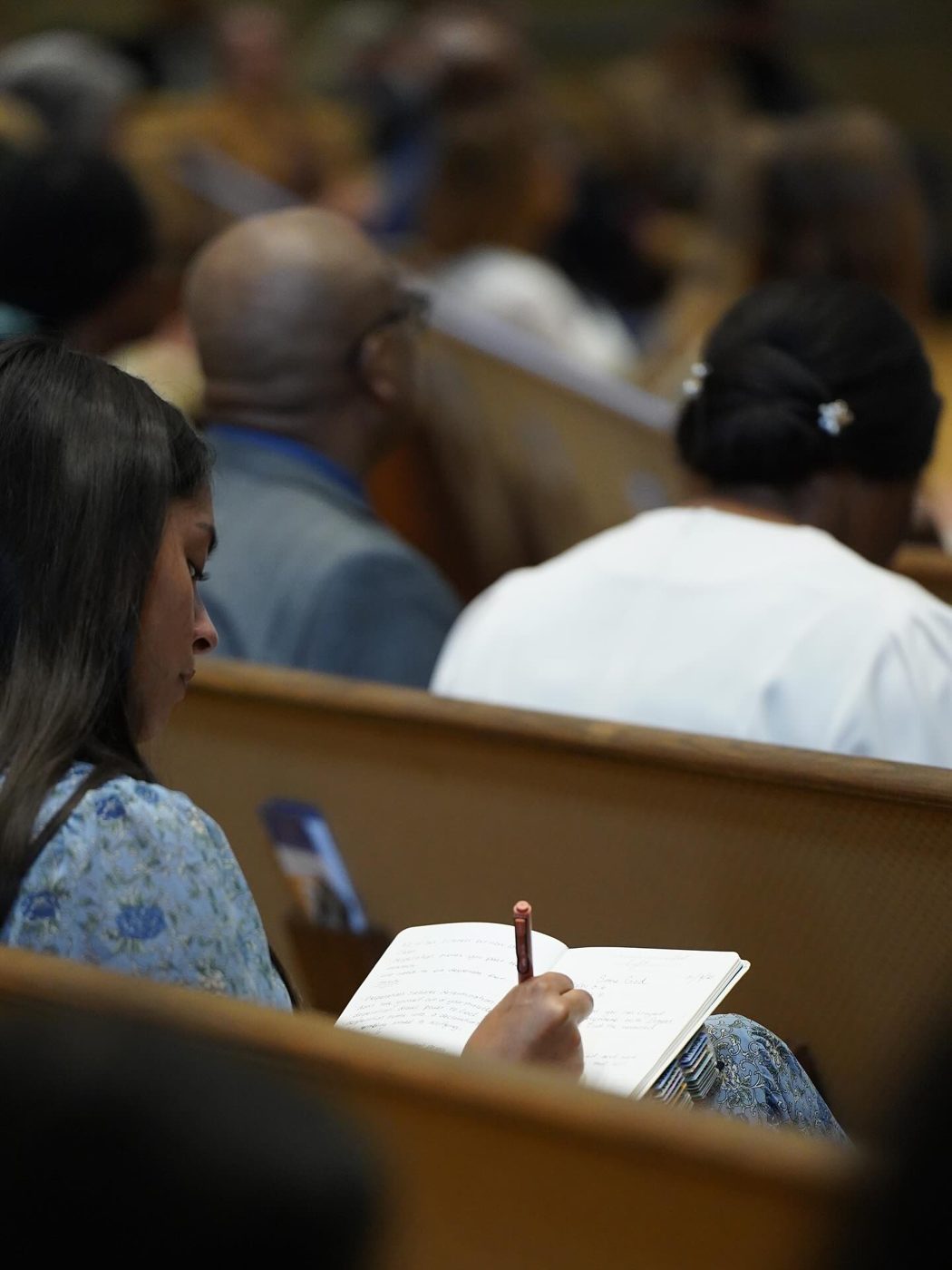 A woman taking notes in a notebook during a Bible class
