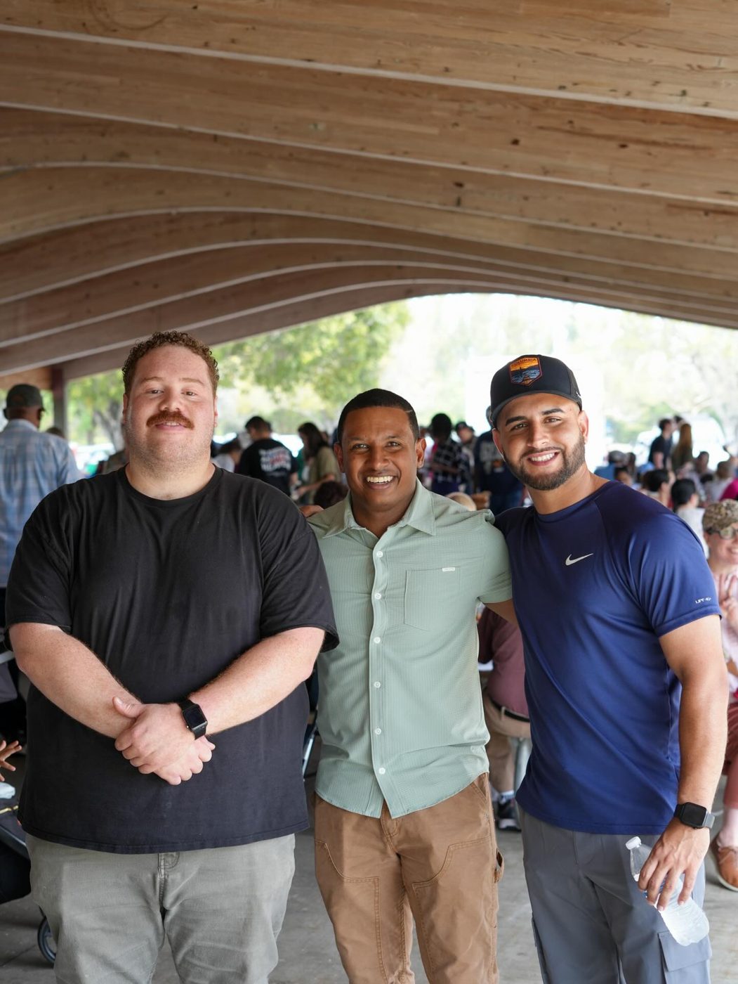 Three friends smiling together under the picnic pavilion