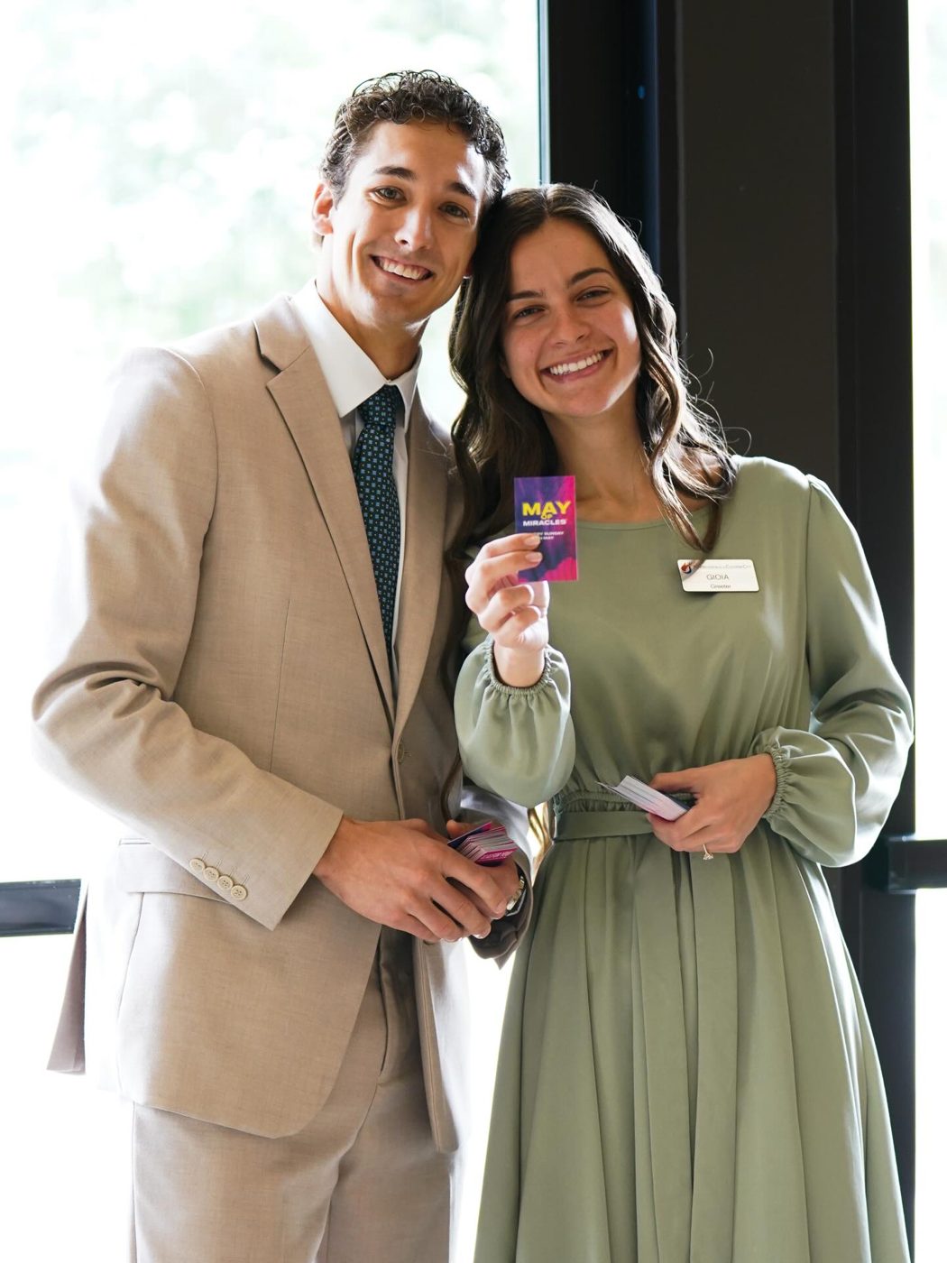 A young couple from the welcome team smiling with name tags