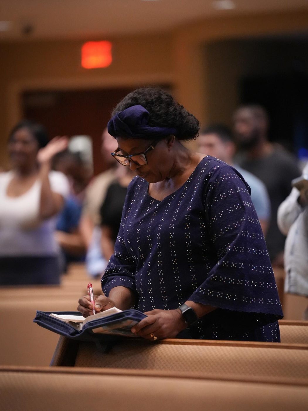 A woman writing notes in her Bible during class