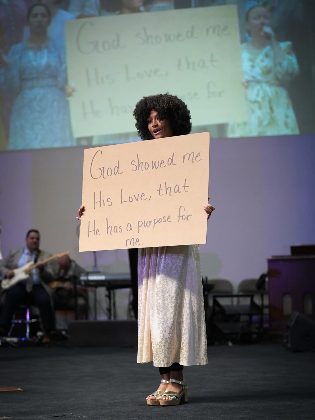A woman on the platform holding a handwritten testimony sign