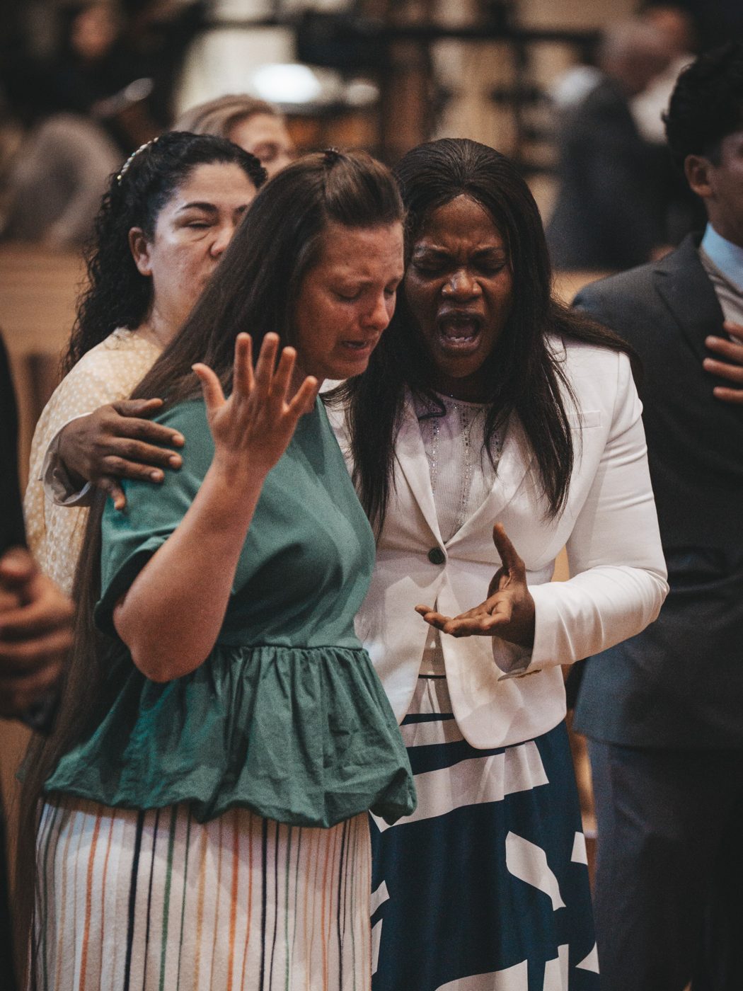 Two women praying together, one with her arm around the other